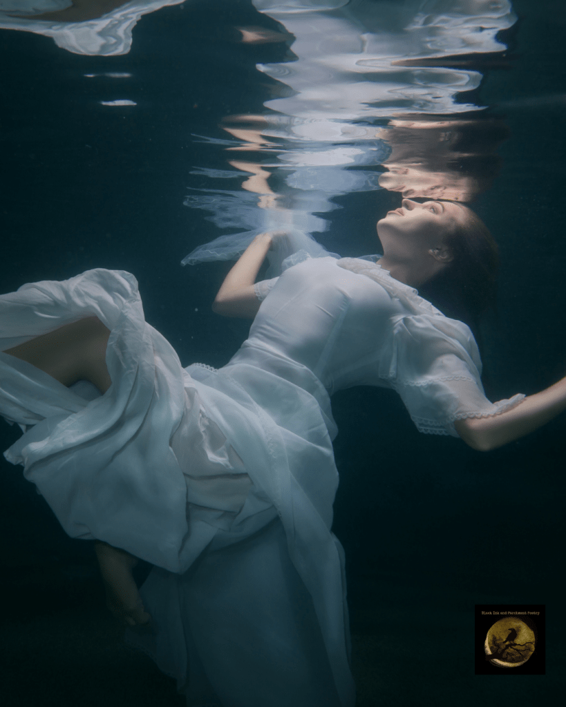 A woman in a flowing white dress gracefully floats underwater, with her hair and garment billowing around her, creating an ethereal and serene atmosphere.